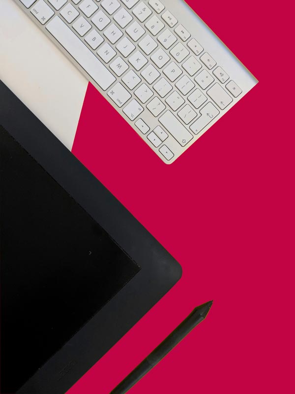 Schreibtisch mit Tastatur und Stift auf pinkem Untergrund
